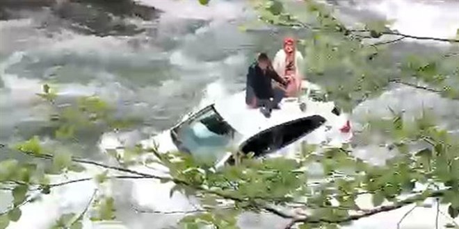 Dereye uçan otomobilin üzerine çıkıp kurtarılmayı beklediler