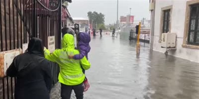 Şiddetli sağanakta polis memuru sudan geçmeye çalışan anneye yardım etti