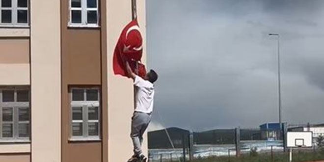 Okul önünde direğe dolanan bayrağı tırmanarak çözdü