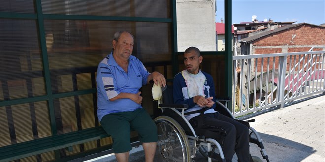 Engelli oğlu için her gün saatlerce otobüs durağında oturuyor