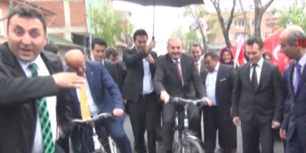 Korumalar bisiklete binen bakana şemsiye tuttu