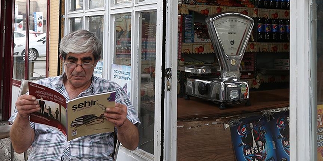 Müşteri yoğunluğuna rağmen elinden kitabı düşürmüyor
