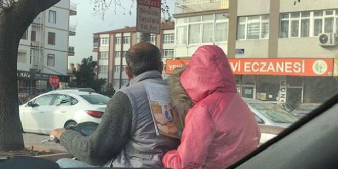Trafikte motosiklette kitap okuyan çocuk dikkat çekti