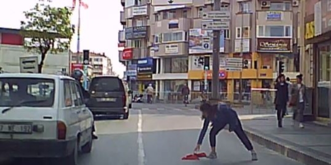 Yola düşen bayrağı araçlar üstünden geçmesin diye aldı