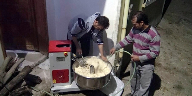 Muhtar, yaşlı kadınların kışlık ekmek hamurunu yoğuruyor