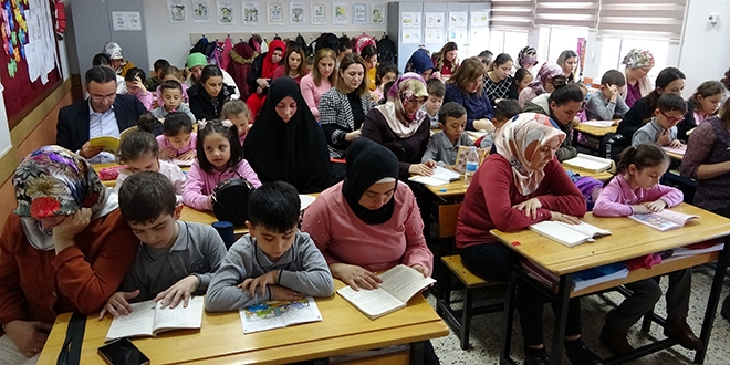 Veliler, çocuklarıyla aynı sırayı paylaşıp, kitap okuyor