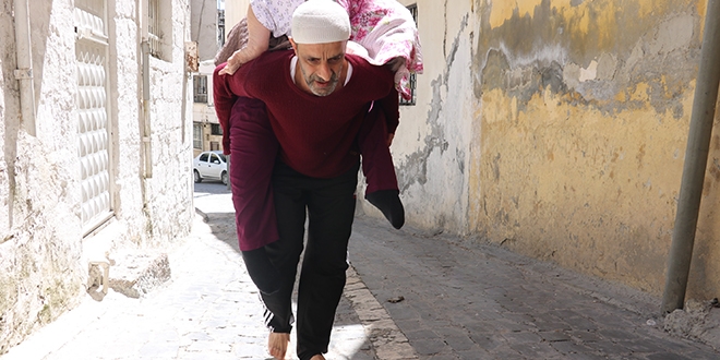 Yatalak annesini sırtında gezdirdi