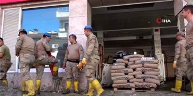 Mehmetçik, çamurdan çıkardığı Türk bayrağını temizleyerek duvara astı